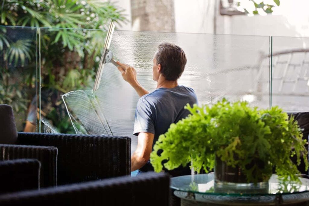 A man cleaning glass on a patio at a commercial cleaning company.