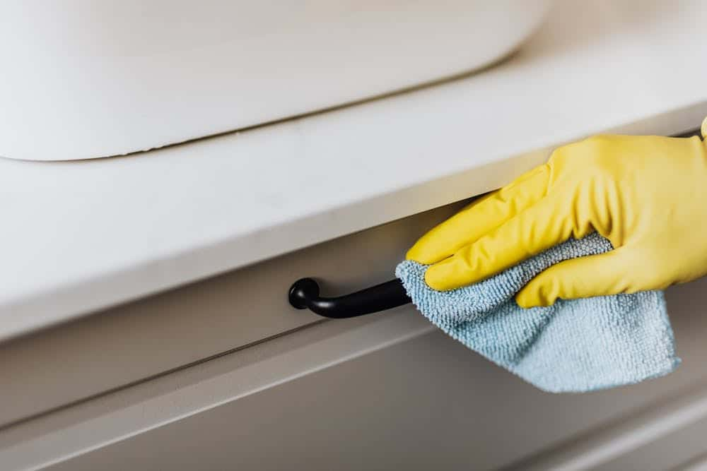 A person wearing yellow gloves cleaning a sink. Professional cleaning services by Local House Cleaners.