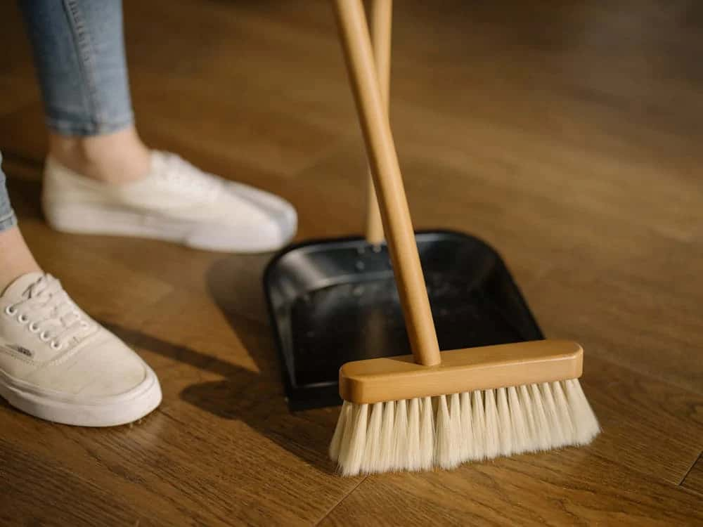 House cleaner using broom to sweep floor.