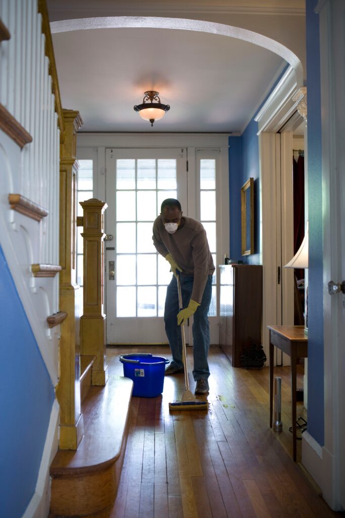 Man in a sweater mopping a hardwood floor