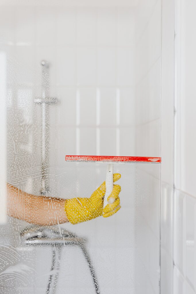 A person squeegeeing a glass shower curtain